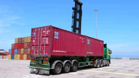 Haifa, Israel - May 11, 2020: Hyster container handler lifting a Red Shipping container off a truck and stack it on a storage platform.