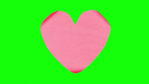 Timelapse footage of crumpled paper in the shape of a heart on table. Shot in 4k resolution with green screen background