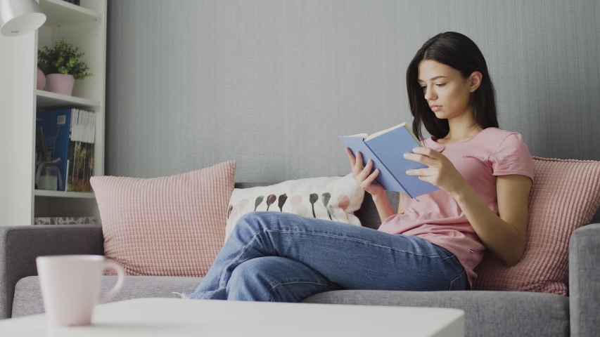 Woman reading a book and realxing on sofa at home