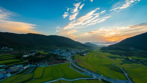 Time lapse High angle sunrise beautiful landscape rice fields on terraced with road to village and mountain of Jeollanam-do, Yeosu-si, Myodo-dong, South Korea.30 fps