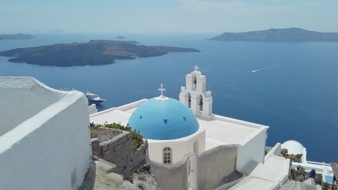 Panoramic view of Three Bells of Fira blue dommed church over caldera and vulcano island with anchored Cruiser ferry boats, Santorini, Greece