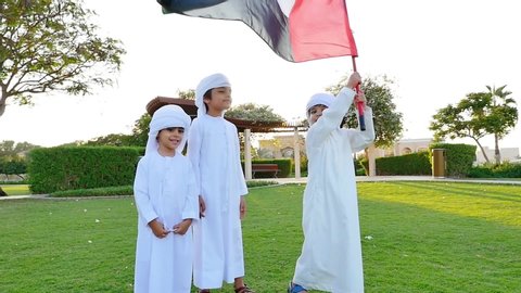 Kids playing outdoor on the meadow. Children wearing traditional united arab emirates kandura having fun
