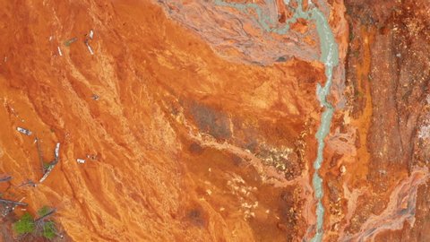Acid rivers flowing from an industrial copper mine pollute the environment. Orange soil is contaminated with heavy metals from an industrial plant. Aerial view