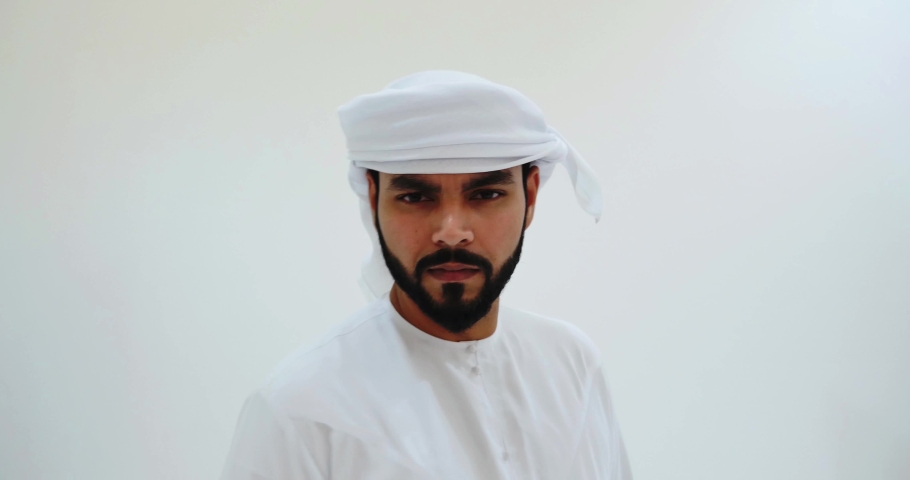 Handsome man with united arab emirates traditional clothes posing in a studio. Young businessman wearing kandura outfit 