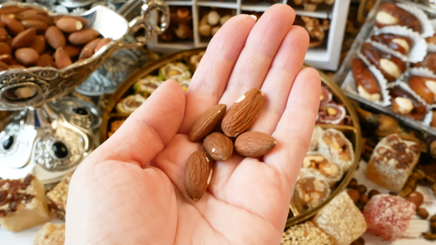 Eastern sweets with nuts, candy, metal vase, dates on wooden background, closeup