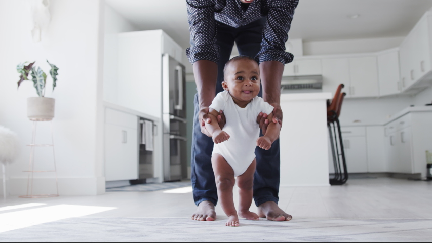 Close up of father encouraging smiling baby son to take first steps and walk at home - shot in slow motion Royalty-Free Stock Footage #1053167303