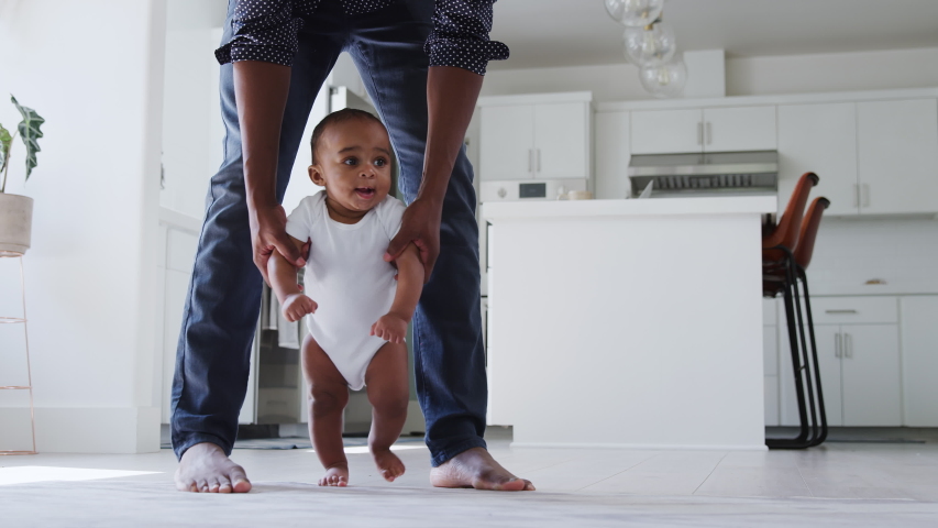 Close up of father encouraging smiling baby son to take first steps and walk at home - shot in slow motion | Shutterstock HD Video #1053167306