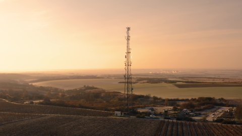 Communication transmitter tower in the countryside aerial view drone footage. Cellphone network antennas amitting radio waves of many frequencies