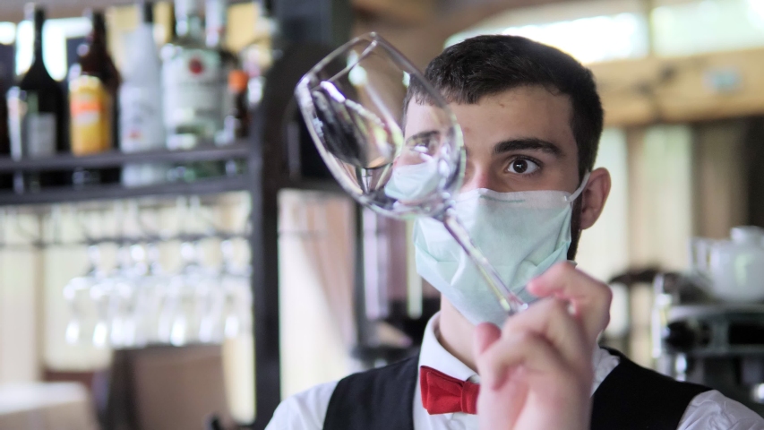 A waiter in a medical protective mask serves the table in the restaurant Royalty-Free Stock Footage #1053172208