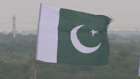 Establishing shot of a Pakistani national flag waving above a house in Punjab, Pakistan.