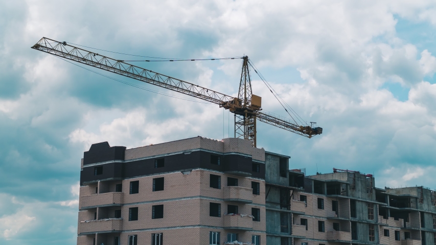 Timelapse footage of a high crane works on building site with a house.