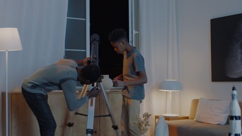 African American black family - father and son, using telescope to explore moon surface. Stay home, learning from home. Shot on ARRI Alexa Mini
