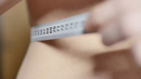Close-up video of young woman measuring her waist with measuring tape.