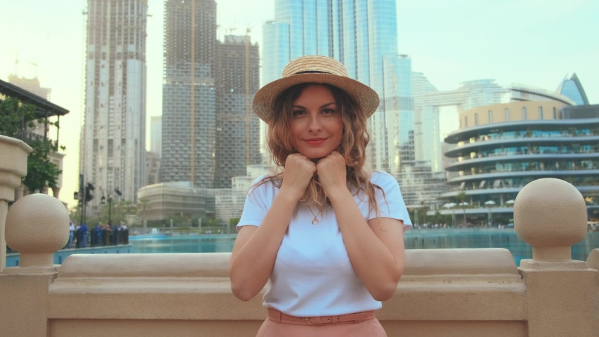 Cheerful happy joyful young woman tourist, red long loose hair cheerfully throws. cute Girl spinning, dancing, hands raised. Smiling face. Backdrop  modern skyscrapers Dubai UAE 4k 2020 Go Everywhere Royalty-Free Stock Footage #1053185555