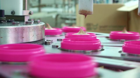 Ice Cream Factory. Pink plastic jars are filled with chocolate ice cream.