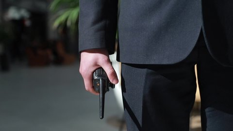 The guard holds a walkie-talkie in his hand. Hand of a security guard holding an intercom in his hand.
