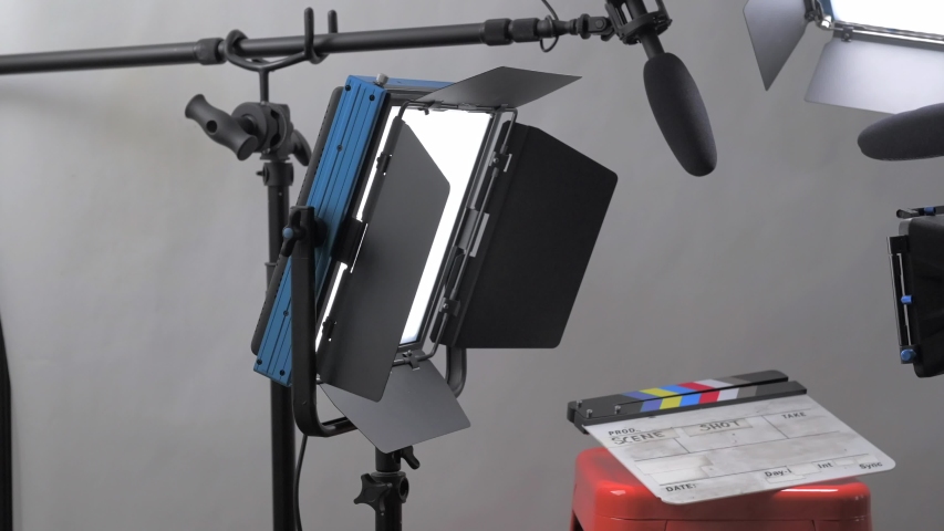 Slider dolly panning shot moving through a professional video production film set with camera, lights, and microphone all set up for an interview in a studio setting.  Royalty-Free Stock Footage #1053196613