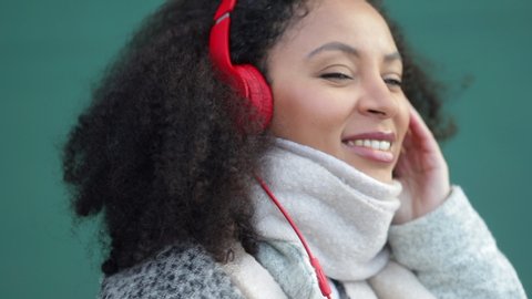 mixed race female wearing headphones listening to music moving with beat of song spbi. concept device, wind, outdoors. female dancing happily, vibing to track sound