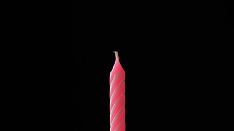 Candle fire at celebration birthday cake blowing at black background isolated.