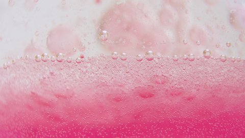 Macro shot of fine bubbles rising, In A glass with pink Liquid, slow motion
