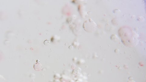 Macro shot of fine bubbles rising, In A glass with pink Liquid, oil and water, slow motion