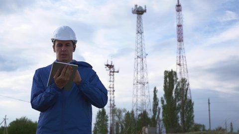 Telecommunications engineer working on digital tablet records data for maintenance of telecommunications network. Engineer design, repair and installation of satellite and telecommunication networks.