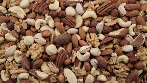 Variety of nuts, almonds, cashews, brazil nuts, walnuts, pecan, macadamia, peanuts, hazelnuts,  camera movement with slider