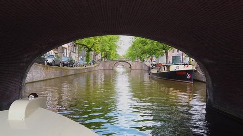 Tourist boat sailing under a bridge in Amsterdam. Bridge over the river, Amsterdam. People walk the streets in Amsetrdam
