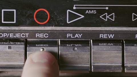 Man finger pressing some buttons on an old retro vintage cassette tape player: play, rewind, fast forward, stop