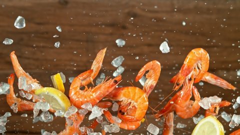Super Slow Motion Shot of Flying Fresh Prawns with Crushed Ice and lemon Slices at 1000 fps.