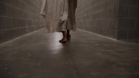 Dramatic, slow motion of Jesus feet walking through prison hallways.