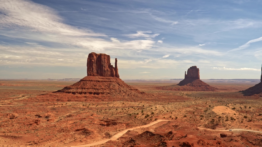 Monument Valley, United States. Orange sandstone buttes in Colorado Plateau. Rocks of different forms. Blue cloudy sky. Panning shot, 4K