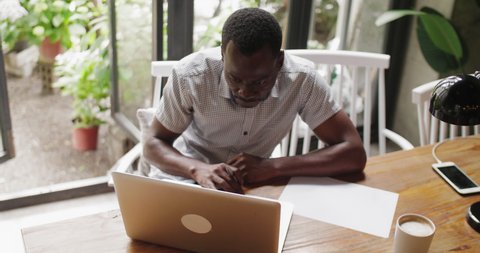 Top view of one African man typing on laptop in the office writing notes serious businessman working with laptop indoor black adult student study online