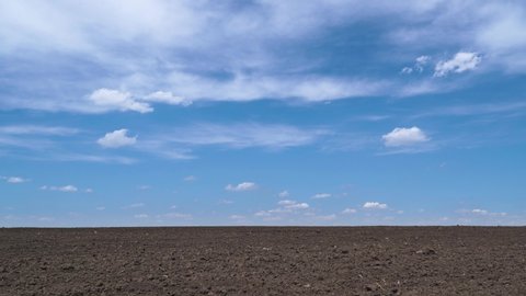 timelapse of plowed field, soil and clouds of a bright sunny day - concept of agriculture
