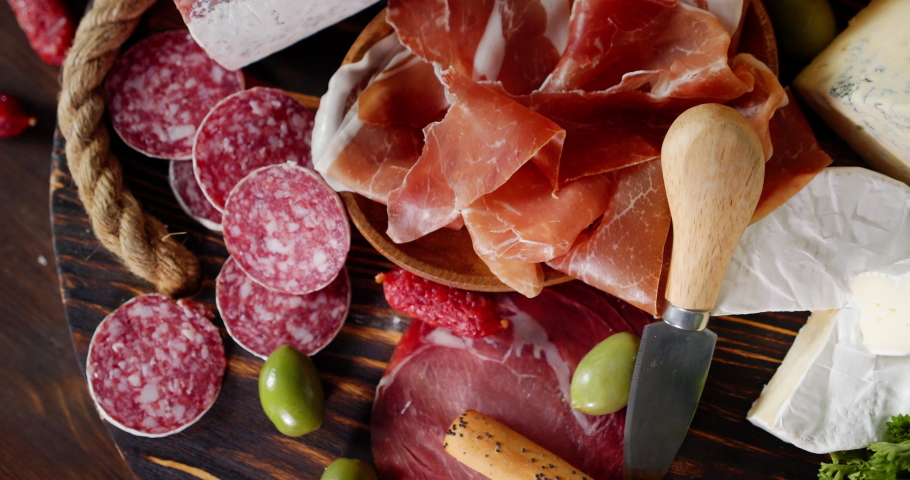 Delicious antipasto meat rotates slowly. On wooden background. Top view. | Shutterstock HD Video #1053236381