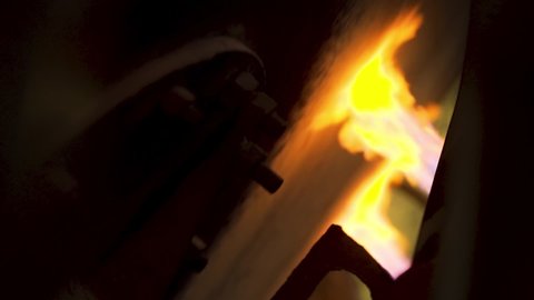 Close up of process of fire quenching. Stock footage. View inside of hot shop of the metallurgical plant, surface quenching by gas flame of rotating detail.