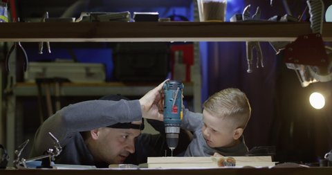 Dad Teaching Little Boy to Use Hammer Nails and Drill Working Together in Workshop a Father and Son Concept