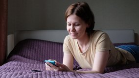 Woman lying on a bed with smartphone, browsing surfing internet