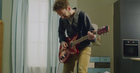 DX MED aucasian male going crazy while playing his electric guitar at home, practicing during quarantine. Shot on RED Helium in 8K with Atlas Orion 2x Anamorphic lens