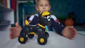 A game with a robot dog. Sad child dreams of a puppy. A boy sits at a table with a toy dog. Kid dreams of making friends. An upset child in his room during quarantine. Loneliness.  - Powered by Shutterstock - Get 15% off with code: PIKWIZARD15