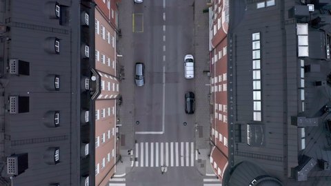 Empty street in Stockholm city, Sweden aerial top down view. Quarantined city, empty abandoned streets during corona virus outbreak. Drone footage flying over buildings, parked cars and street