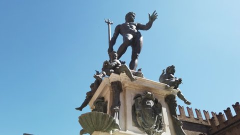 LOOP around Neptune statue-fountain of Bologna city in Italy. Restored in 2018 and located in Nettuno square of Bologna city center. Lower ground view with blue sky and sun rays