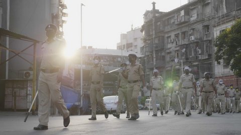 A police force or policemen walking or marching on the road wearing protective face mask during lockdown or curfew amid Coronavirus or COVID 19 epidemic or pandemic, Mumbai, India (May 2020)