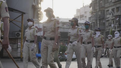 On duty ladies or women police force, constables in uniform marching on the road wearing proactive face mask during city lockdown amid coronavirus or COVID. 19 pandemic in Mumbai, India (May 2020)
