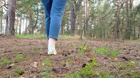 Shooting close-up of woman's legs walking in a steep terrain through the forest, slow motion