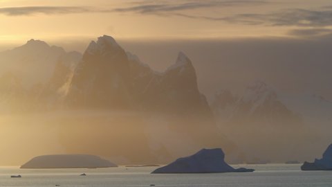 WS Snow covered mountains and Lemaire Channel in fog at sunrise / Antarctic Peninsula, Antarctica