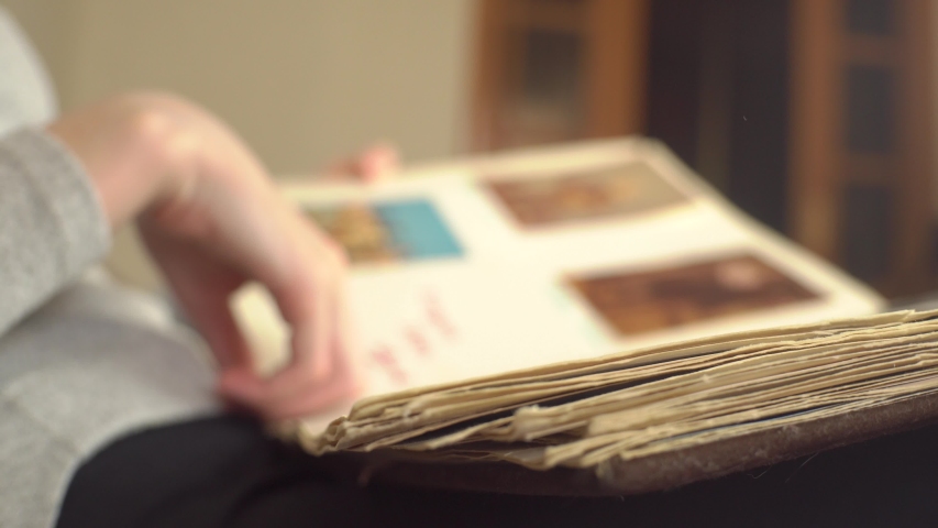 Woman is looking at old photo album at home. A woman recalls the past, as it was before.