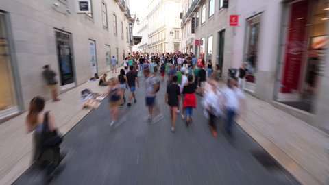 LISBON - JULY 14, 2019: Hyperlapse shot, quickly move up by Rua do Carmo shopping street of Lisbon, people silhouettes around. Typical pedestrian traffic at historic city centre, Baixa neighborhood