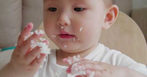 Close up of lovely baby girl eating rice by herself at home Adorable happy Asian baby eating indoor 
