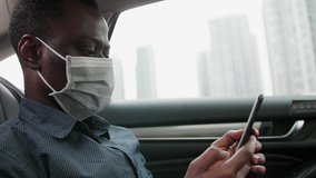 Side view of one black businessman wear mask traveling in the car using mobile phone looking at phone in hand during pandemic of coronavirus Covid-19 - Powered by Shutterstock - Get 15% off with code: PIKWIZARD15